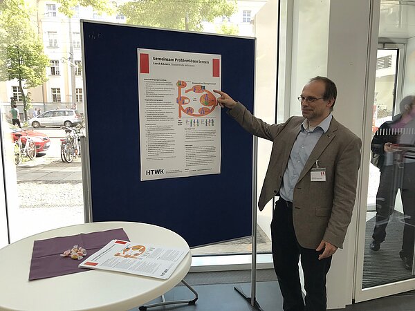Junger Mann zeigt auf ein Plakat