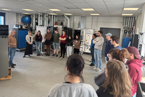 Fabrikraum mit Neonlichtern Seminargruppe steht im Kreis und erhält eine Einweisung