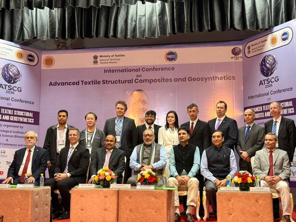 Mehrere Personen sitzen und stehen auf einer Bühne für ein Gruppenfoto