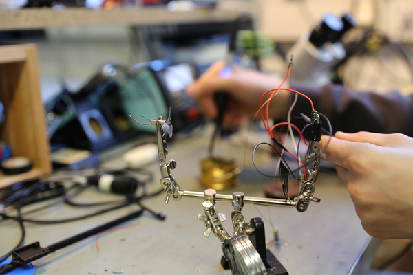 Nahaufnahme einer Hand, die an einem Minirotor und Kabeln arbeitet und Drähte löten will