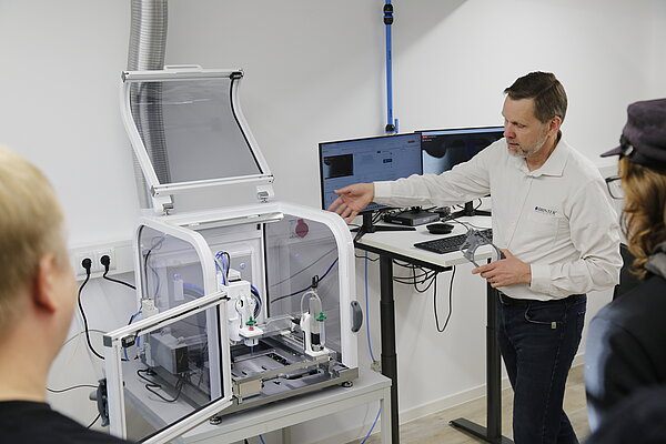 3D-Drucker Mann zeigt anderen Personen 3D-Drucker