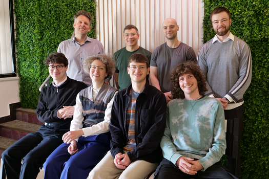 Gruppenfoto Forschungsgruppe CCL vier Personen sitzen auf der Bank aus recycelten Rotorblatt Elementen anderen vier Personen des Teams stehen dahinter, alle schauen in die Kamer