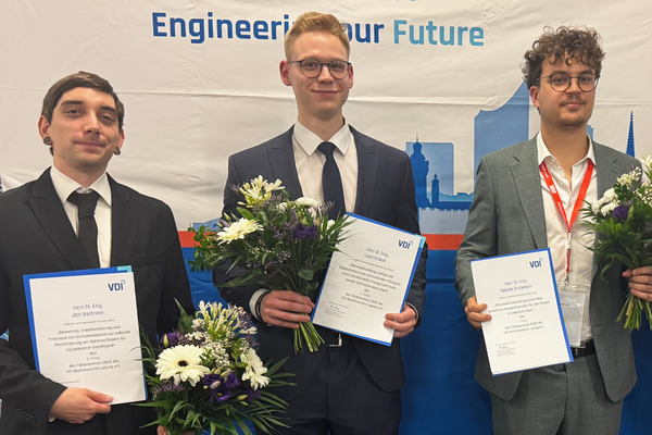 Portraitfoto der drei Preisträger mit Urkunde und Blumen in der Hand