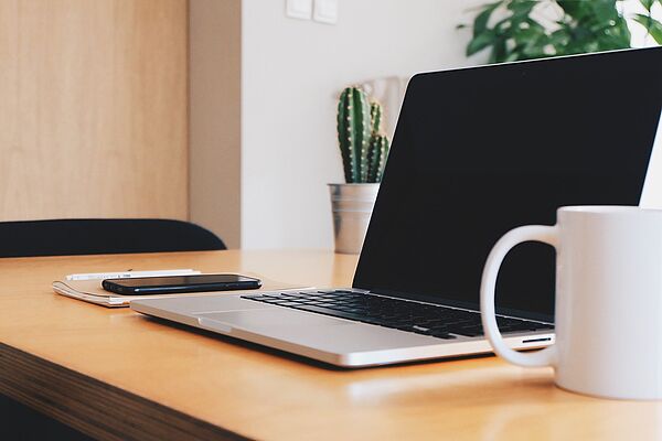 Arbeitsplatz mit Laptop, Tasse und Kakteen