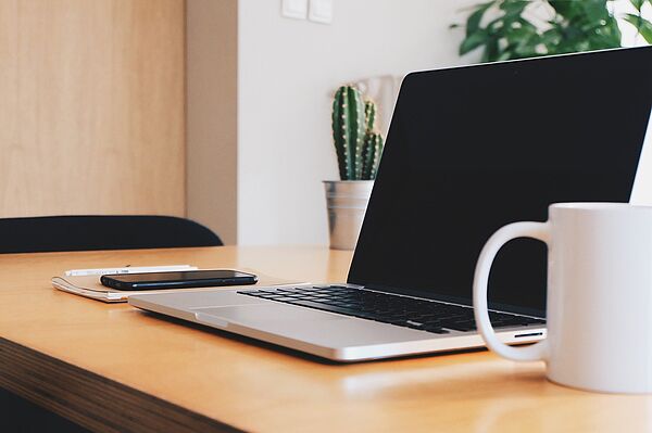 Arbeitsplatz mit Laptop, Tasse und Kakteen