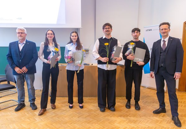v. l. n. r.: Prof. Lutz Engisch, Josepha Eliane Kahnt, Isabell Schäker, Leo Dinkelacker, Alexander Ostrovskis, Prof. Jean-Alexander Müller Gruppe von Studierenden mit Urkunden und zwei Professoren steht in einem Hörsaal
