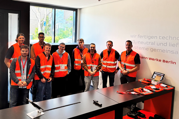 Gruppenfoto in rot-orange leuchtenden Warnwesten in einem großen Büro