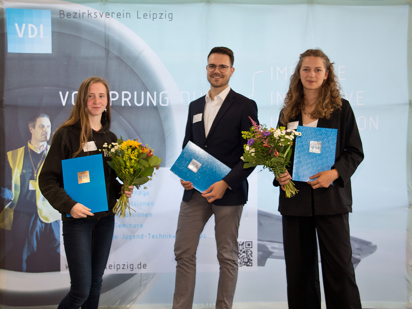 Sie wurden mit dem Förderpreis 2022 geehrt (v.l.n.r.): Lara-Marie Schulze, Tim Wrobel und Vanessa Fock. (Dominic Elias Taraba war zur Verleihung nicht anwesend). (Foto: Quelle VDI Bezirksverein Leipzig e.V.) drei Menschen mit Urkunden und Blumen