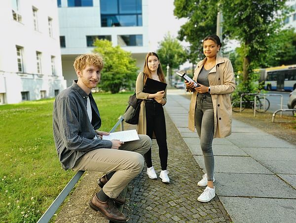 drei Studierende vor der HTWK auf dem Gehsteig