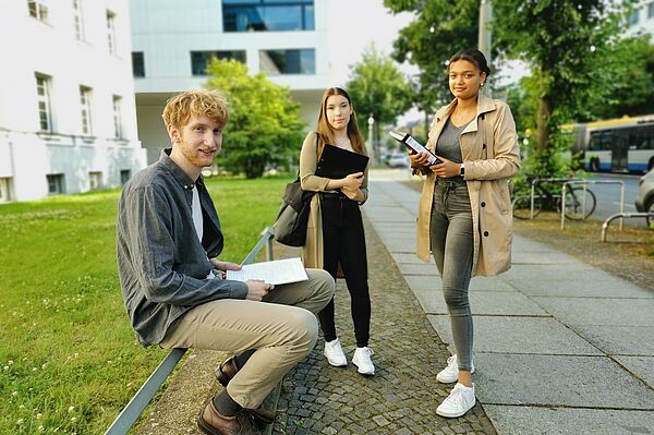 drei Studierende vor der HTWK auf dem Gehsteig