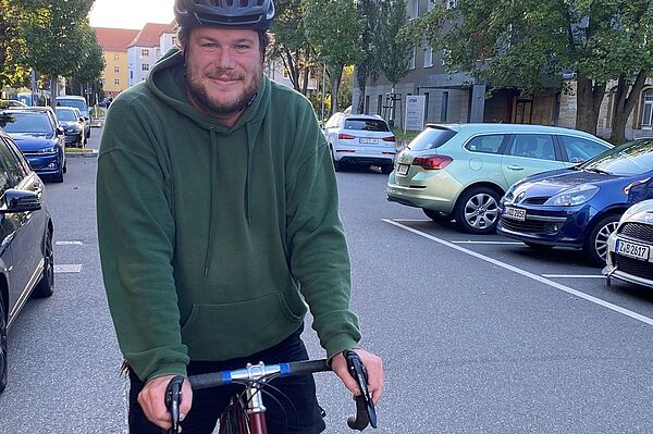 Mann auf Fahrrad mit Helm steht auf Straße