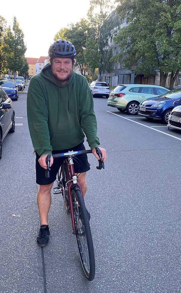 Mann auf Fahrrad mit Helm steht auf Straße