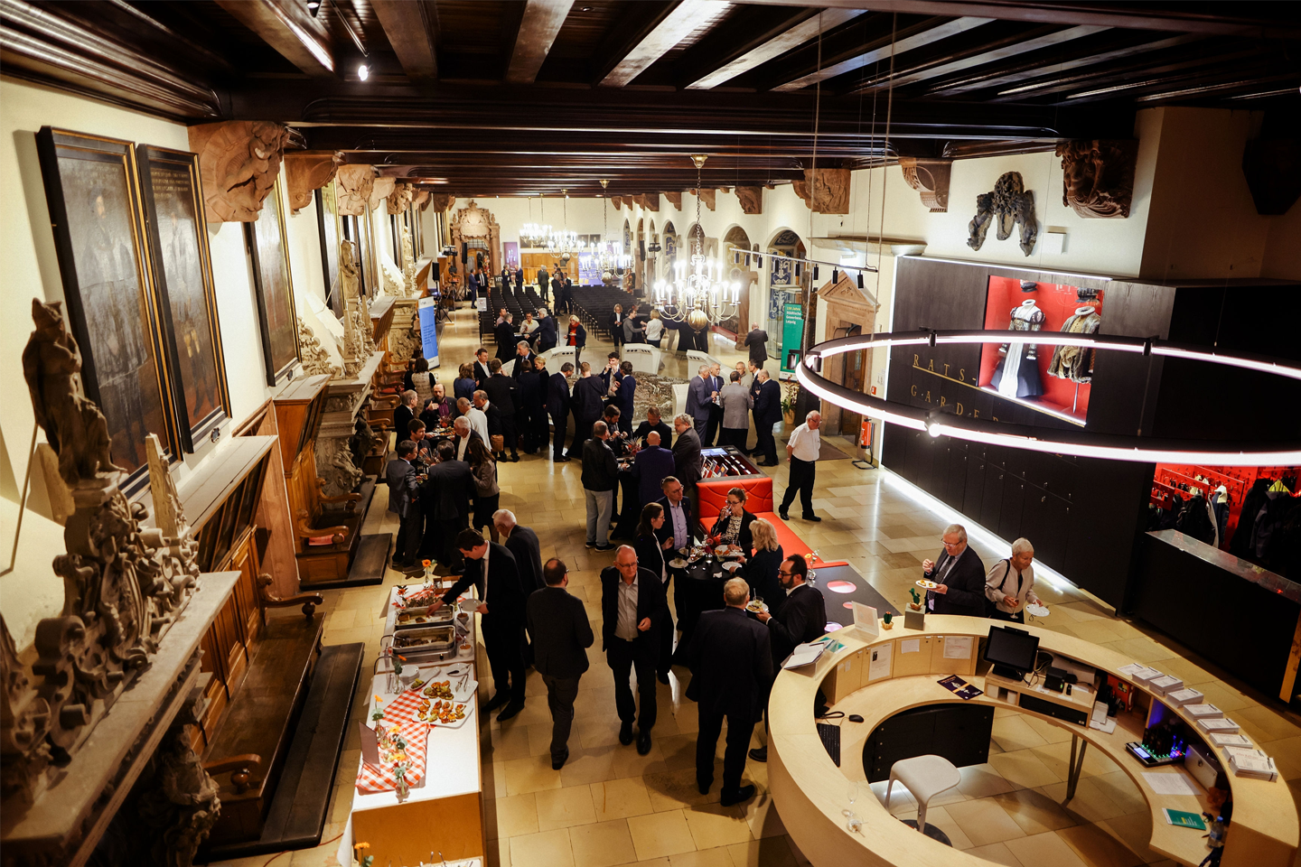 Panoramabild vom Festsaal mit Teilnehmenden bei Gesprächen