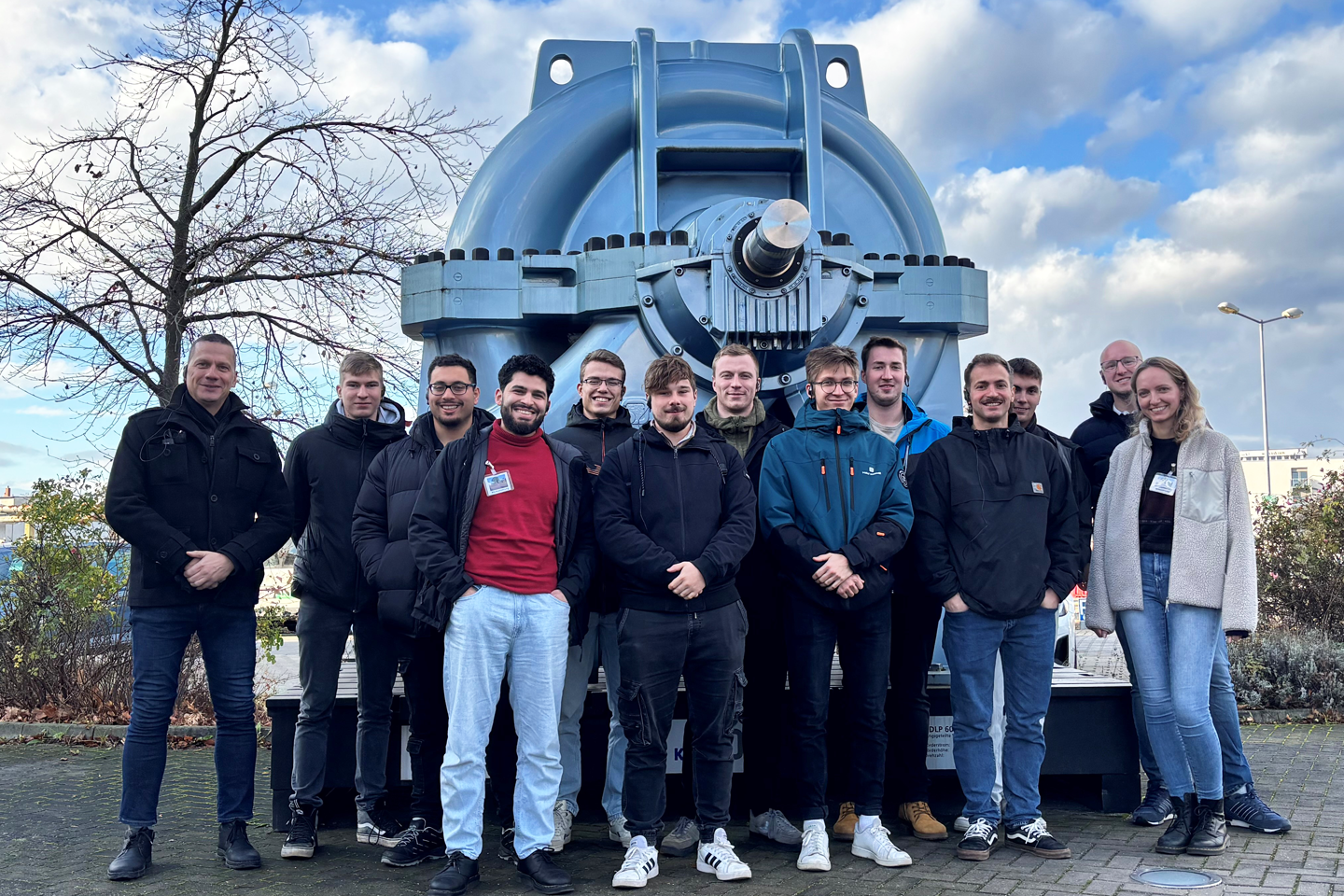 Gruppenfoto vor einer großen dunkelblauen Pumpe im Freien