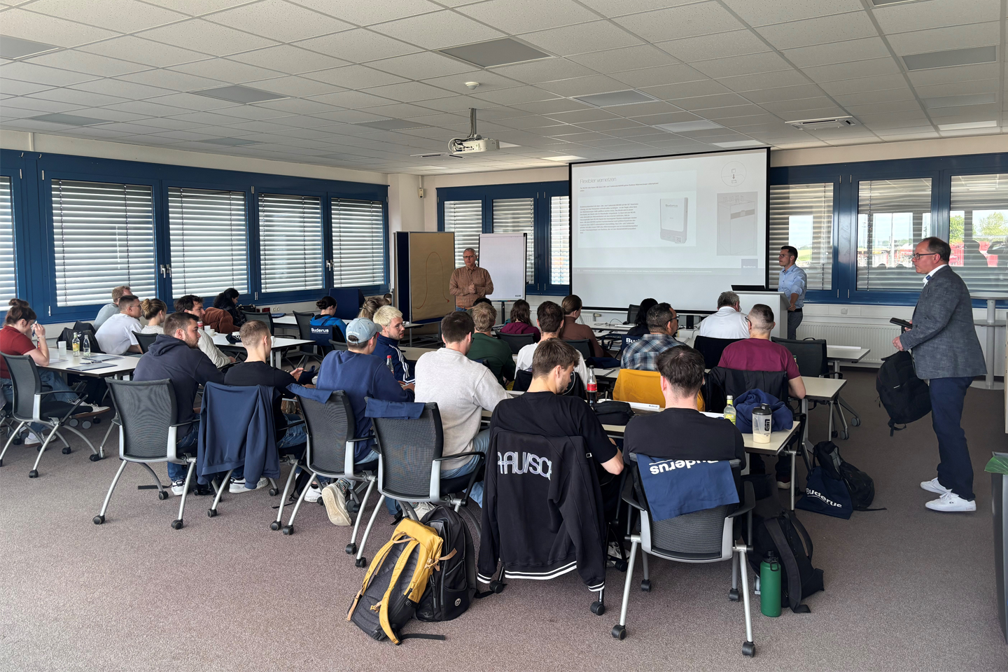 Studierende der Seminargruppe sitzen in einem Seminarraum vor einer Leinwand und erhalten eine Einweisung