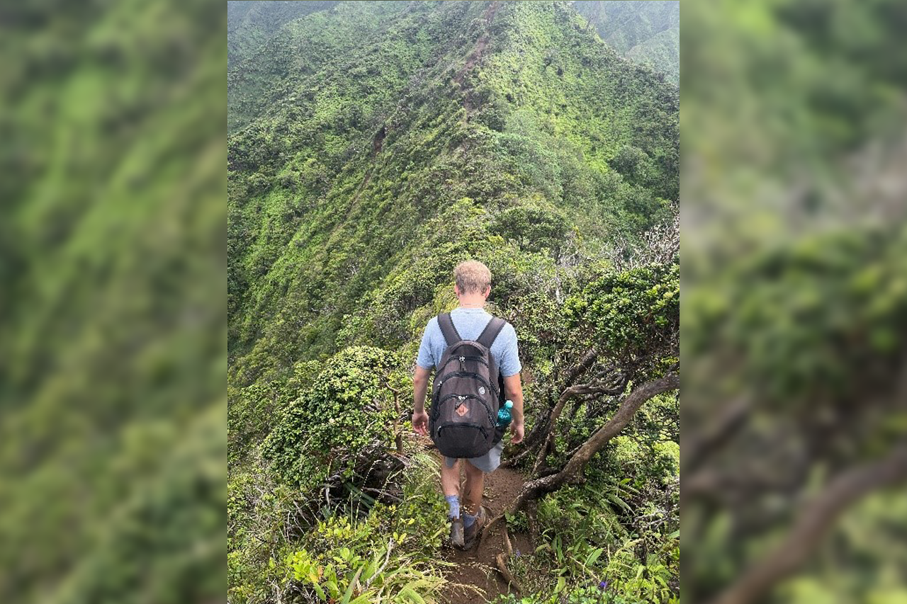 Hiking Student wandert über grünen Bergrücken auf der Insel Oahu