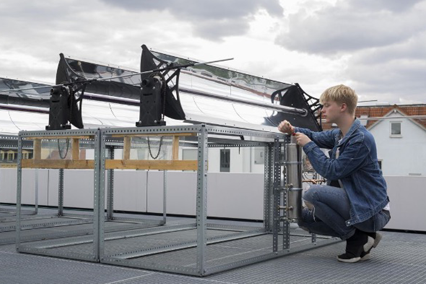 Solar collectors and a student working on the collector in front of them