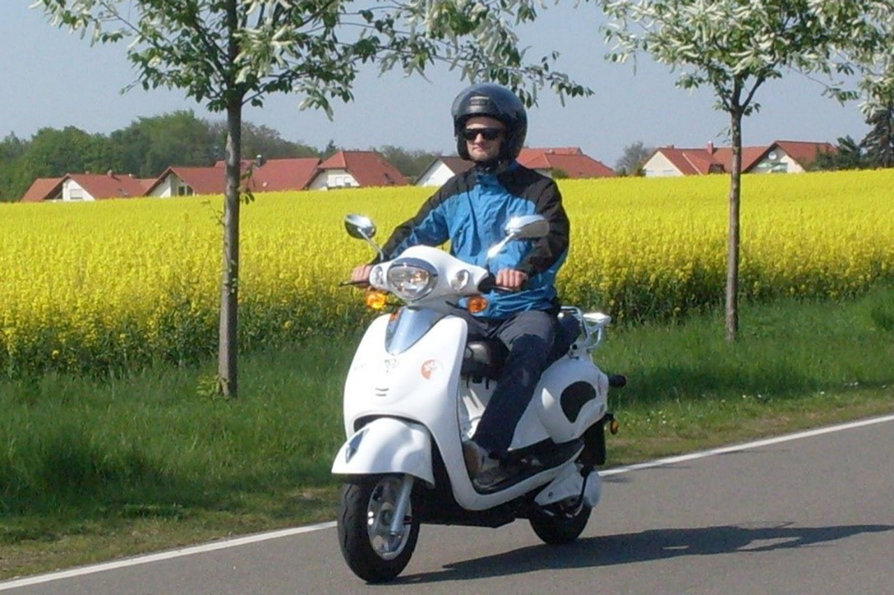 E-Roller-Fahrer, im Hintergrund gelbes Rapsfeld