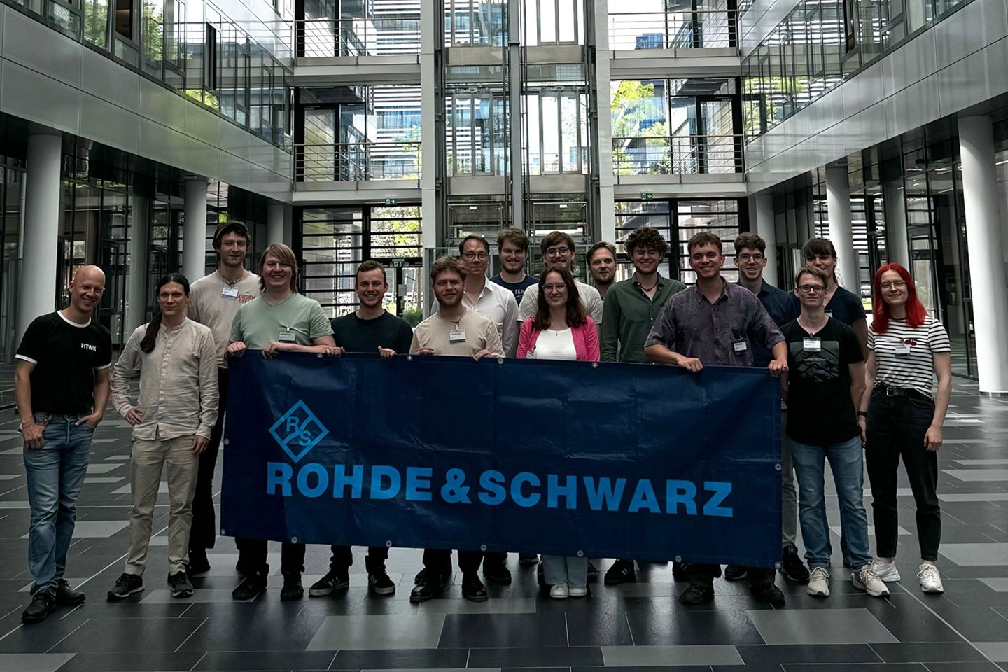 Group photo of the participants, group holding the Rohde Schwarz logo in front of them