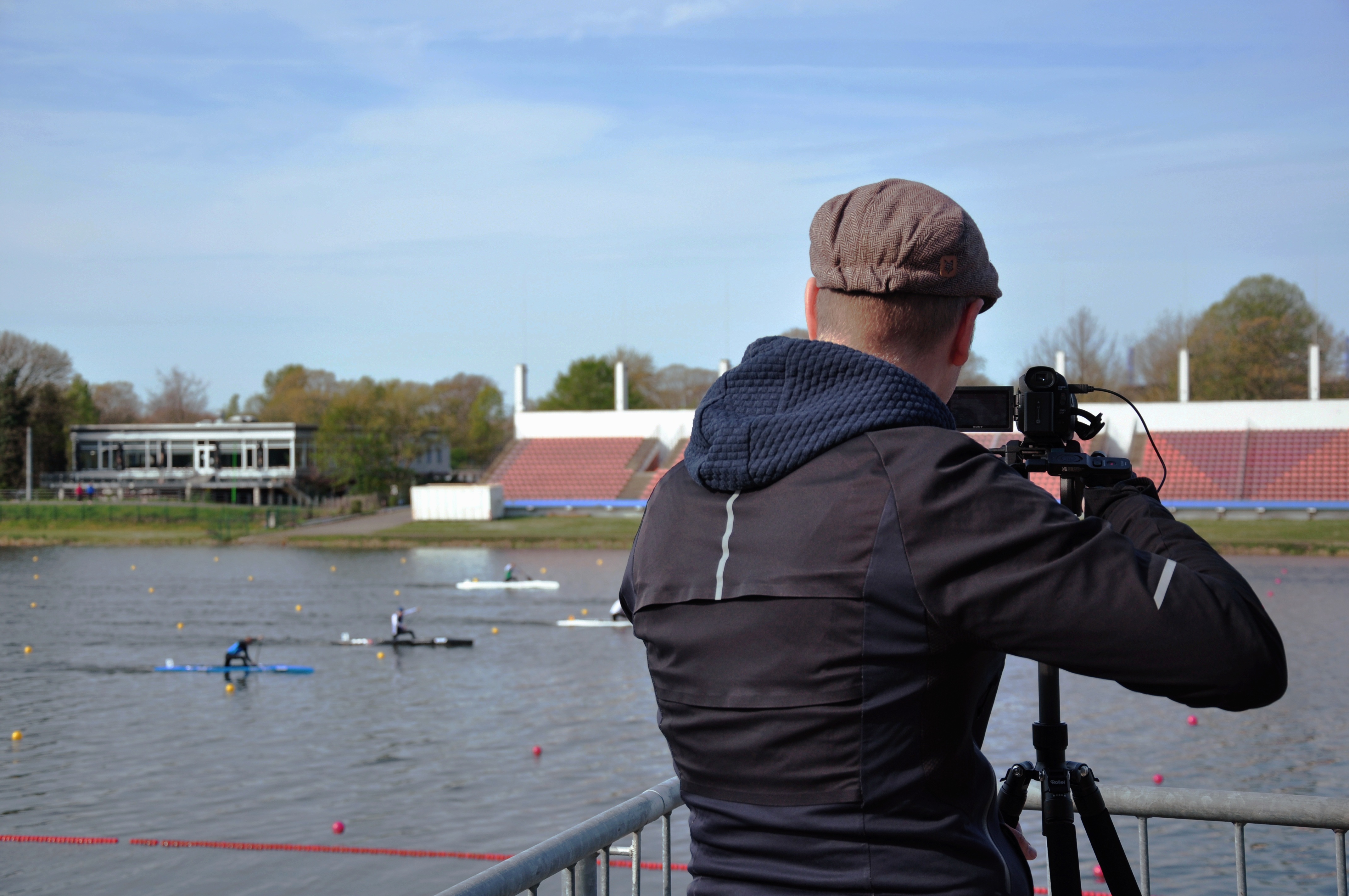 Person films canoeists on the river and can be seen from behind.