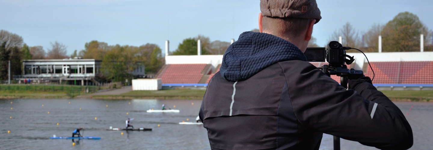 Person filmt Kanuten auf dem Fluss und ist von hinten zu sehen