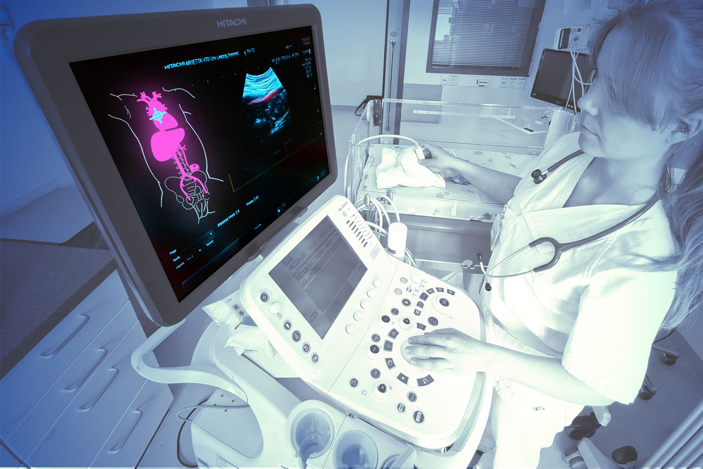A monitor in the foreground displays a scan of organs in bright colors; a scientist stands next to it