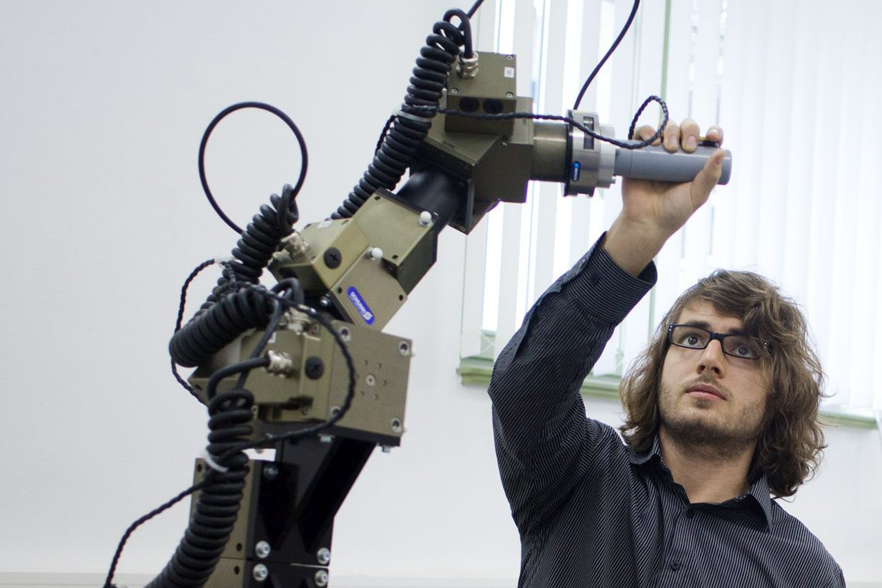 Scientist grasps the arm of an industrial robot model / When clicked, the link leads to the project website
