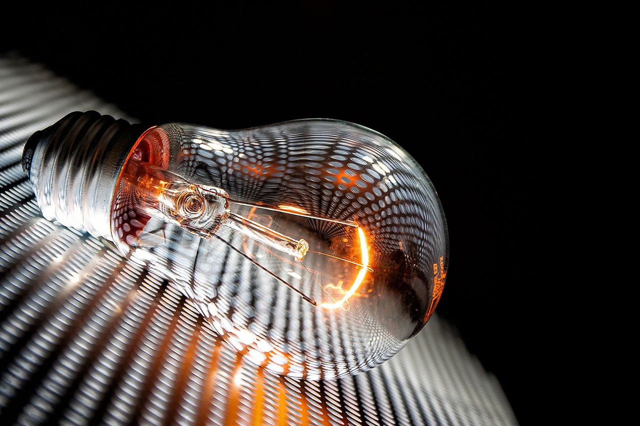A lit light bulb rests on a grid / The link leads to the project website