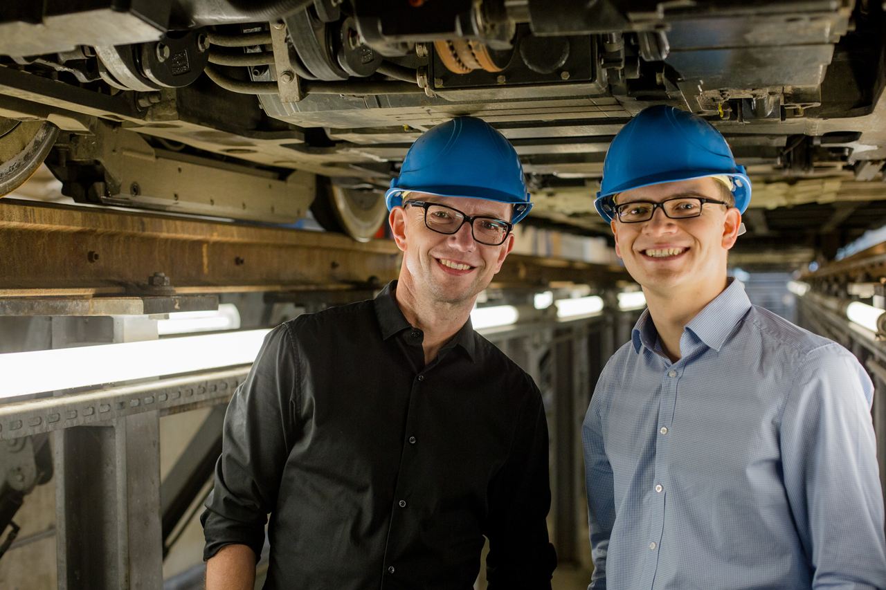 Group photo, blue helmets on their heads, with the chassis of a streetcar in the background / link leads to the project website