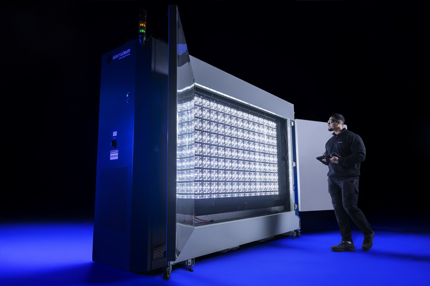 A large cabinet that simulates sunlight; next to it stands a person holding a measuring device