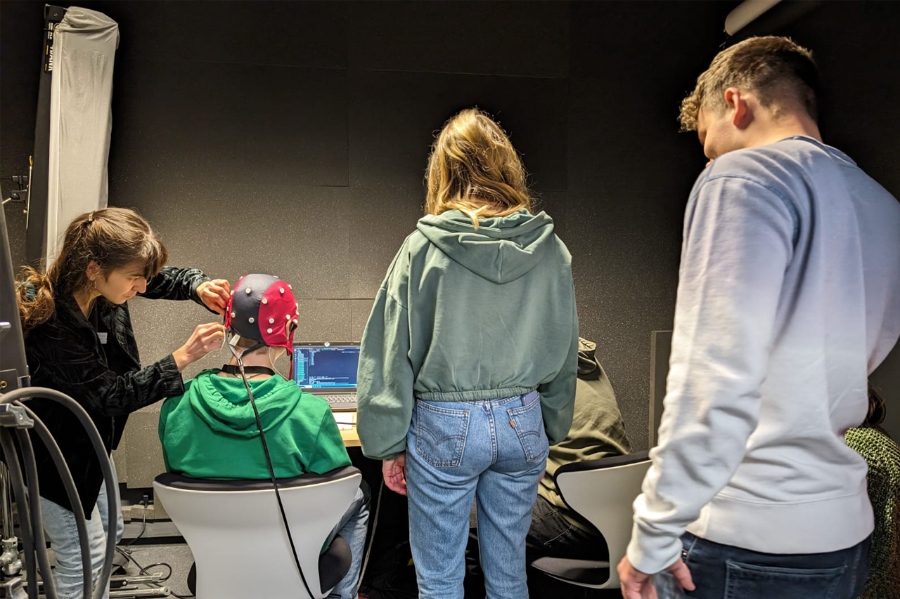 Schülerinnen und Schüler messen mit Kappe Hirnströme beim MPI-Experiment 